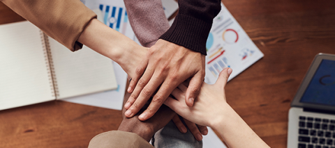 multiple hands piled over one another across a table