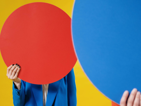 person holding up a red and blue circle in front of their face