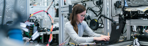 Young woman in equipment room, working on a laptop