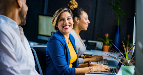 lady smiling to a colleague with fingers on a computer