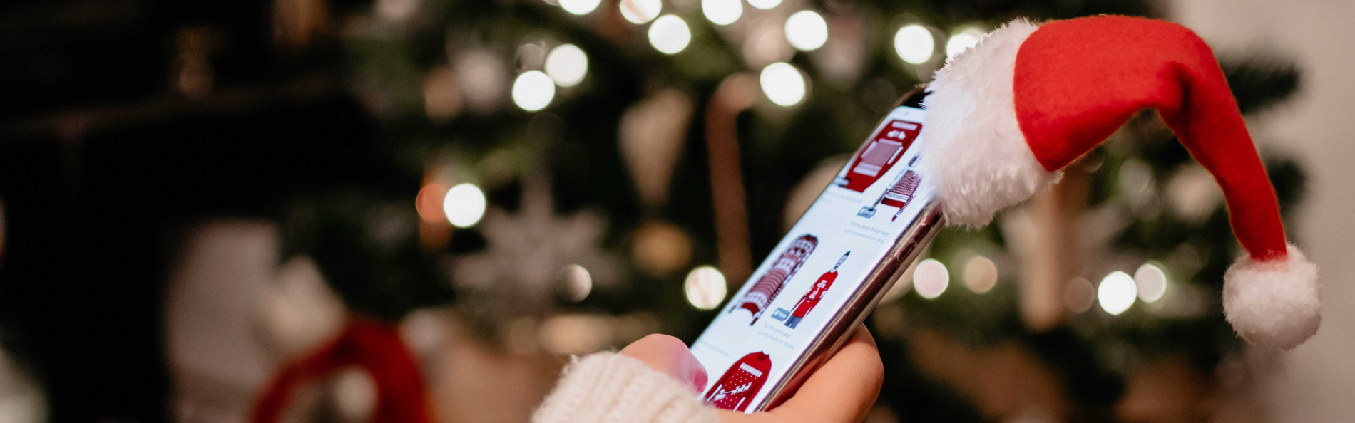 hand scrolling on cell phone with a santa hat 