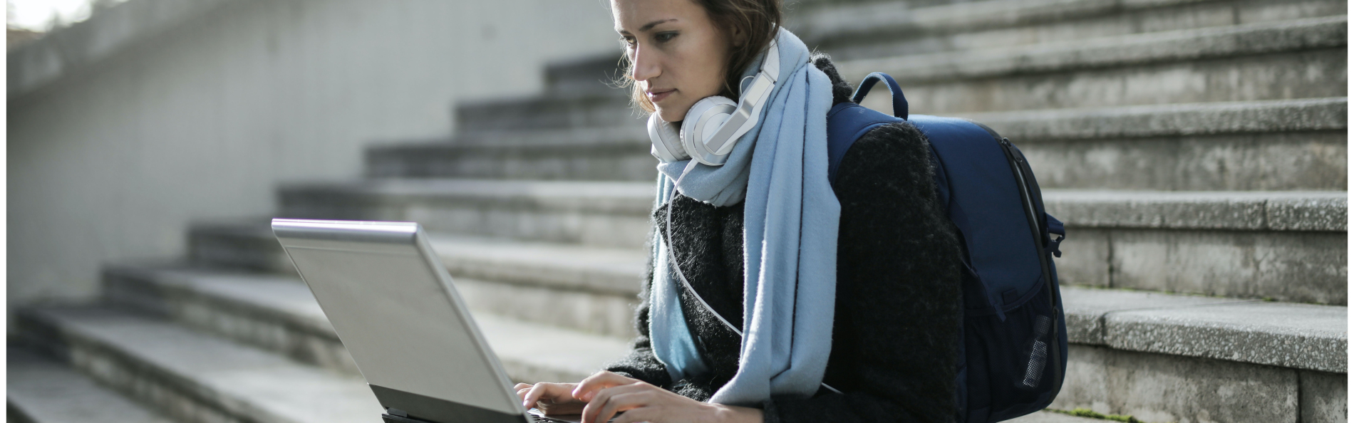 Person sitting outside on stairs using laptop