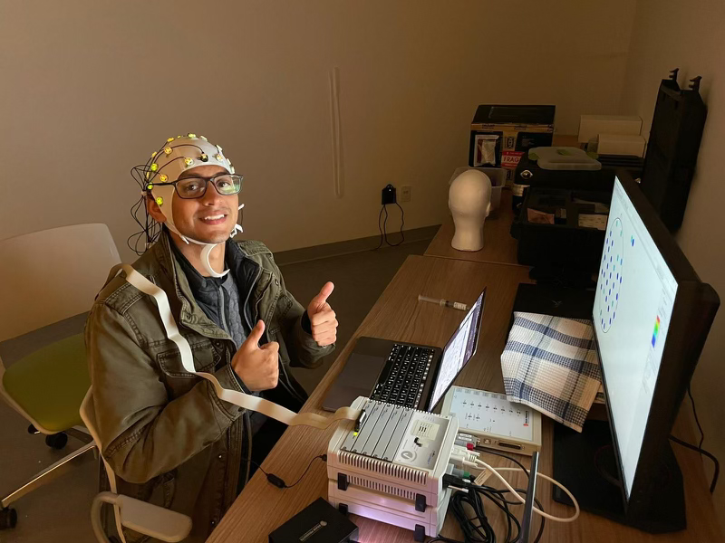Esteban Hernandez-Rivera wearing an EEG cap, sitting in front of a monitor.