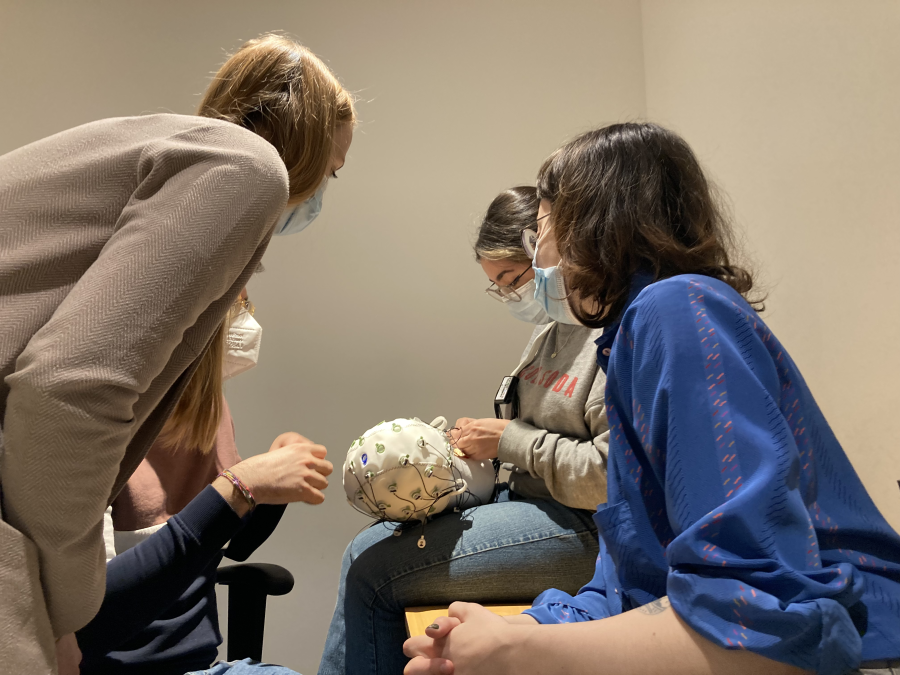 Four people fitting an EEG cap on a foam head