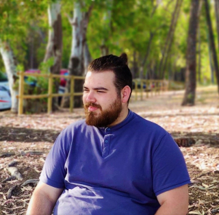 Antonio Iniesta in a blue shirt, sitting in a park.