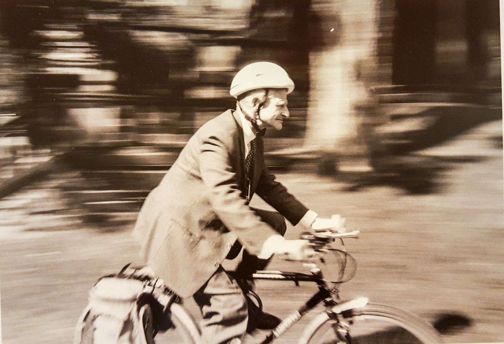 John Durnford cycling outiside of Chancellor Day Hall. Sepia toned photo.