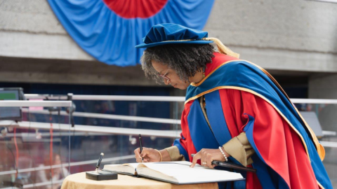 Professor Adelle Blackett [a middle aged Black woman with shoulder-length hair] signing the register at the SFU convocation