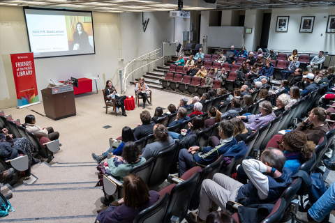 Lecture hall filled with audience members watching a conversation.