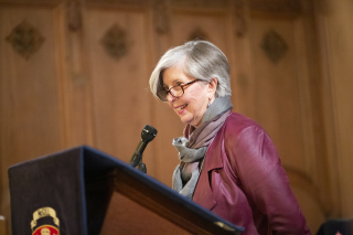 Ann Vroom speaking a wood podium.