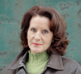 Headshot of author and journalist Carol Off in front of teal wall