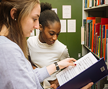 Two students looking at a Manuscript in the Music Library stacks.