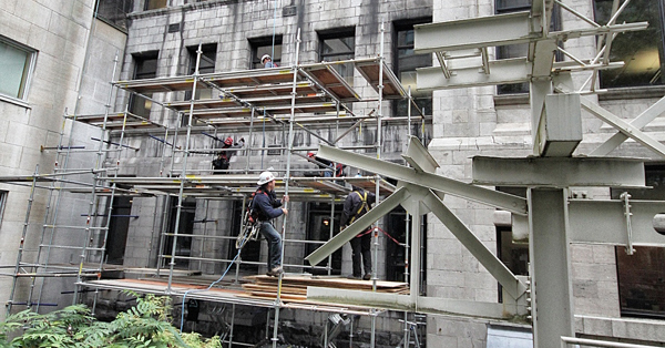 Workers on scaffolding working on exterior of Schulich Library