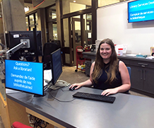 Librarian at desk smiling at camera.