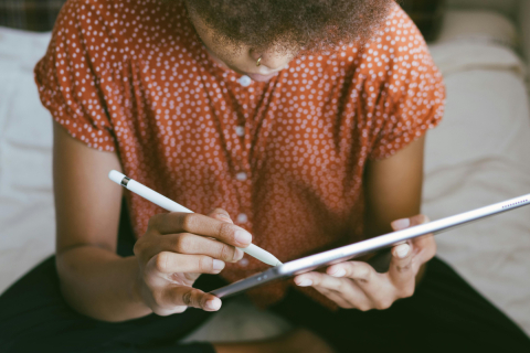 Person looking at e-reader/iPad holding a stylus.