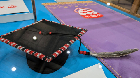 Foreground: beaded McGill graduation cap. Background: Beaded McGill fall featuring red and white crest on purple fabric.