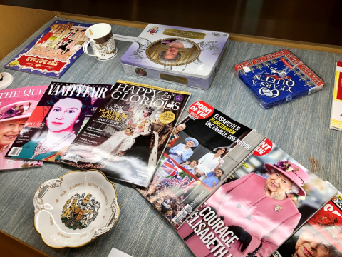 Installation view of exhibition featuring magazines, a plate, a mug, and a cookie tin.