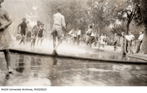 black and white photo of chidlren playing in the spray of a fire hose