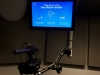 Screen with the words "Welcome to the One Button Studio" in white on blue. With a camera and microphone in the foreground.