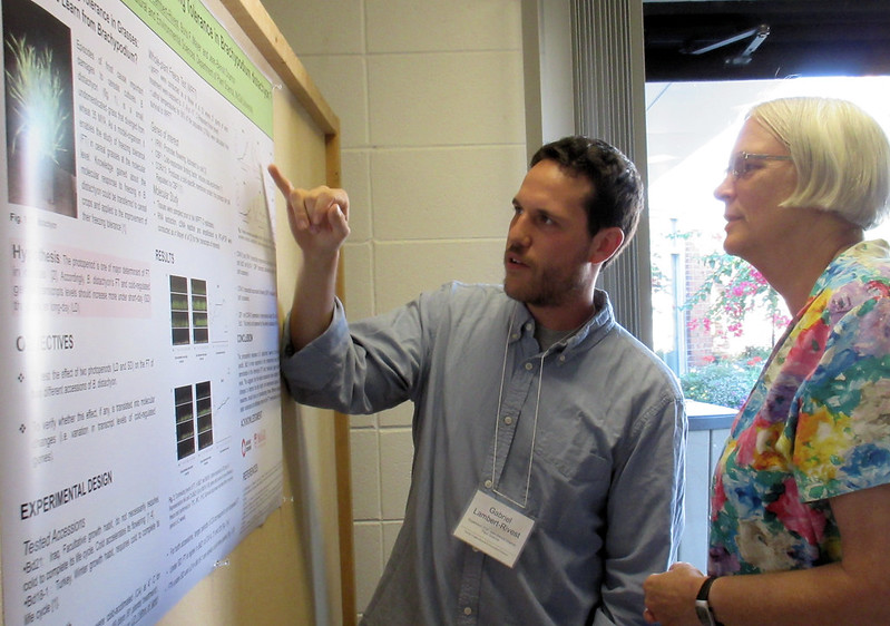 A student explains his research poster to an observer
