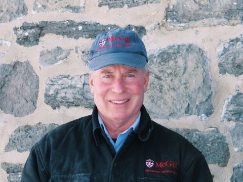 Paul Meldrum wearing a McGill cap, standing against a stone wall backdrop