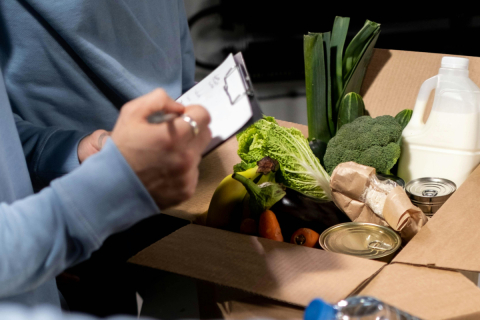Volunteer checks off a list beside box of food donations