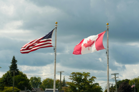 Canadian and American flags fly in the wind