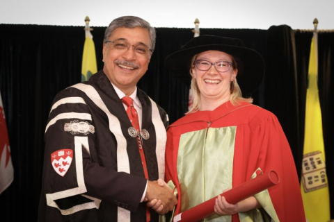 Ronholm in regalia shaking hands with Principal Deep Saini as she receives her prize.
