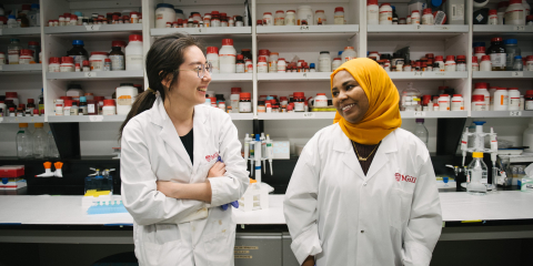 Two McGill graduate students in a lab smile at eachother