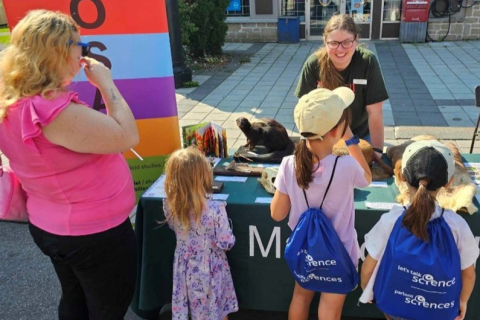 Person at a table explaining information to children
