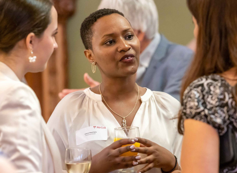A Mastercard Foundation Scholar mingles with two staff members at an event
