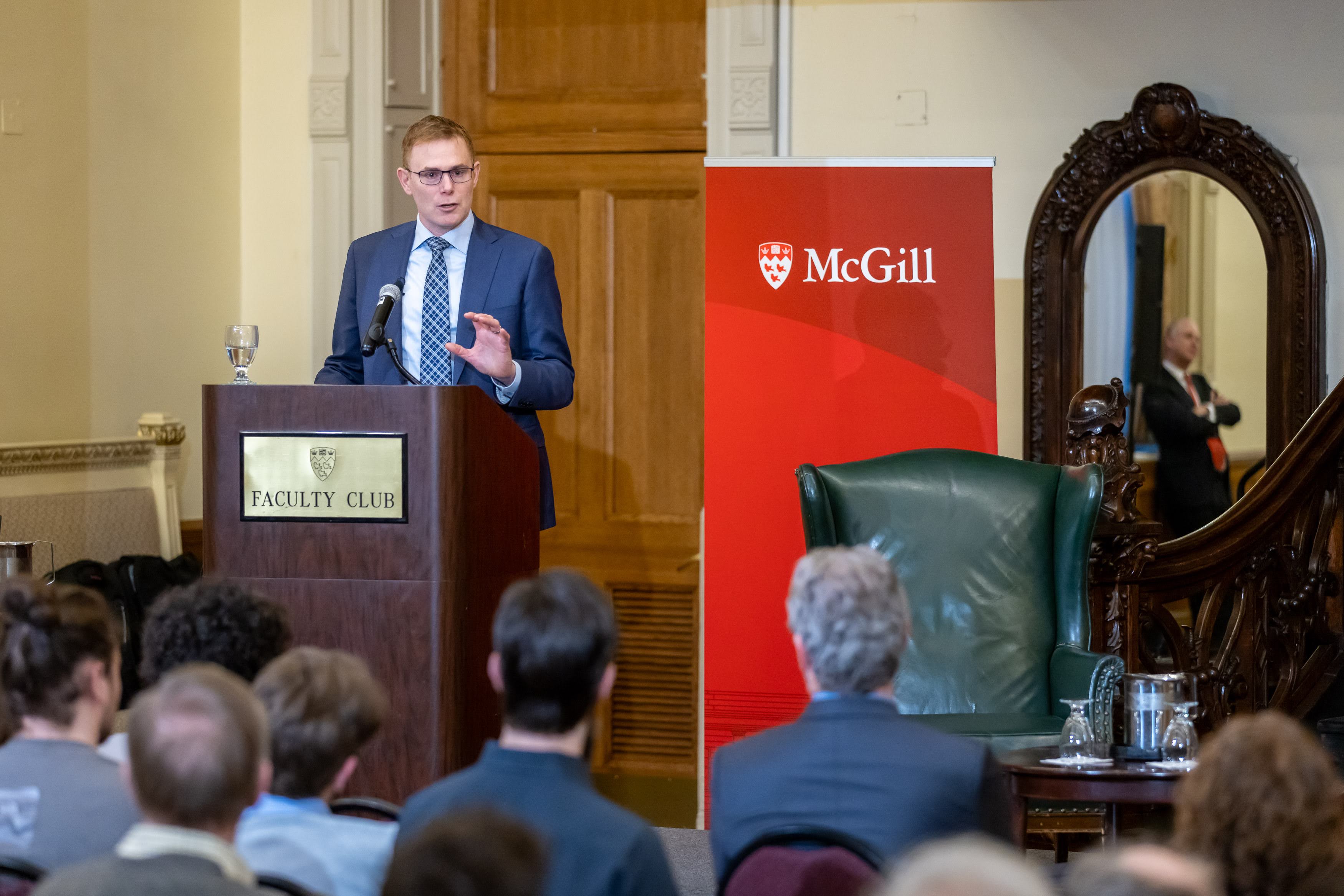 Andrew Leach giving a lecture on stage at the McGill Faculty Club in Montréal.