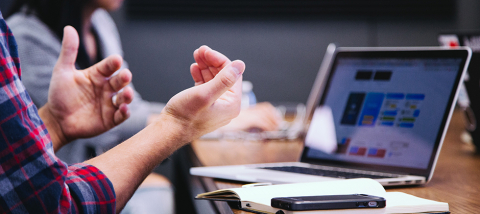 Hands gesturing above a laptop on a desk