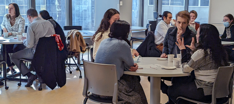 Students discussing in classroom around round tables