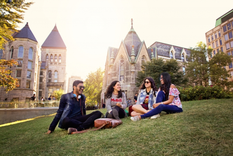 Four McGill students sitting on campus grounds grass