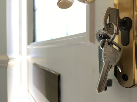 photo of a front door with a key on the lock