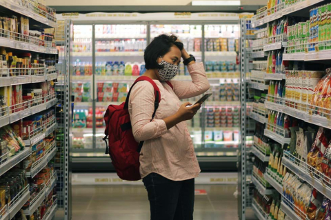 Woman standing in grocery aisle looking at phone