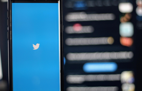 A phone screen displays the Twitter app