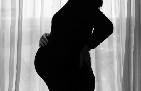 A pregnant person holds their stomach