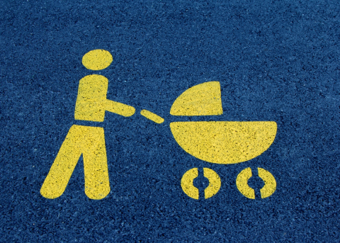 An symbol painted on asphalt depicts a parent pushing a stroller