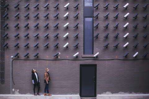 Two people look up at a wall of security cameras