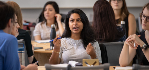 A student in discussion with other students seated around