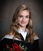 Emily Newell smiling at camera in convocation gown holding red roses with carnations