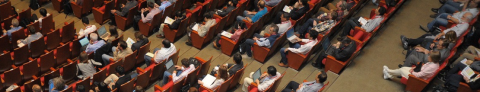 Top view of many people sitting in chairs listening to a speaker