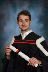 Emeric Bernier in convocation gown holding a diploma