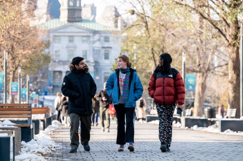 3 students walking towards the Roddick Gates, with Arts Building in view behind, on a winter day