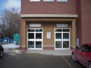 A building with 2 doors and a parking lot in front.