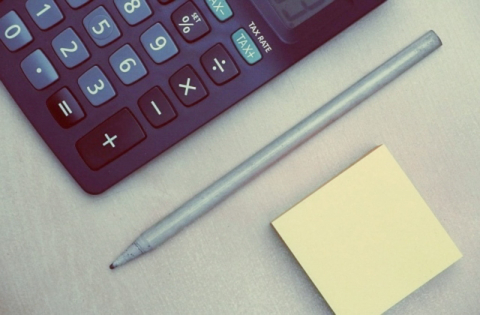 une calculatrice, un stylo et un bloc-notes disposé sur une table