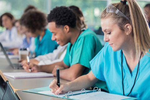 Une table d'étudiants en médecine en blouse prend des notes sur leur bloc-notes.