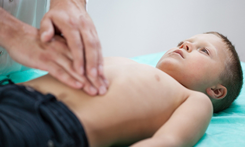 Doctor osculating a child's abdomen.