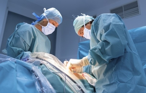 deux chirurgiens masqués et habillés pratiquent une intervention.